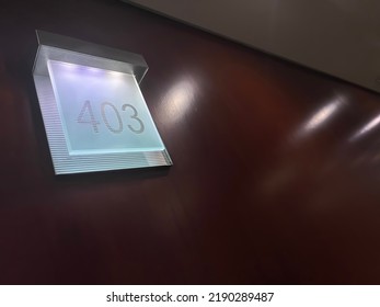 A Dark Wooden Wall Of A Hotel Corridor With A Backlit Bluish White Methacrylate Sign With The Room Number 403