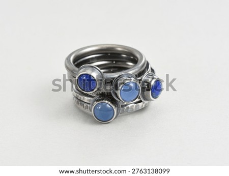 Darkened silver rings stack on white background. Hand made sterling silver rings with round blue cabochon gemstones, like lapis lazuli and blue chalcedony. Silver jewelry darkened uzing oxidisers.