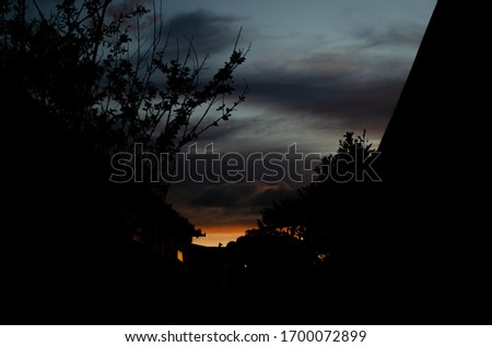 Darker exposure of a sunset in between two houses