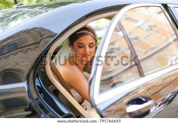 dark-haired bride jewelry head sits in a black car on\
your wedding day