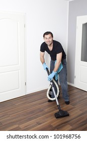 Dark-haired cleaner vacuums the flat