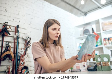Dark-haired girl choosing nutriments for her pet in a pet store - Shutterstock ID 1994945579