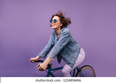 Dark-haired joyful lady chilling during photoshoot on bike. Winsome caucasian girl with wavy hair sitting on bicycle. - Powered by Shutterstock