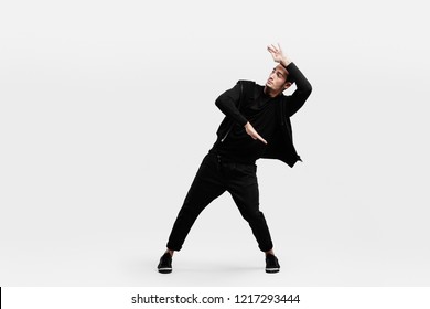 Dark-haired Stylish Man Dressed In A Stylish Black Clothes Is Dancing Street Dance. He Makes Stylized Movements With His Hands