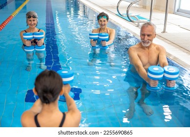 Dark-haired woman leading a water fitness class - Powered by Shutterstock