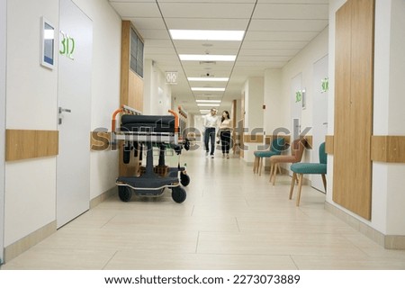 Dark-haired woman and middle-aged man walk along the hospital corridor