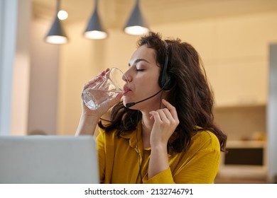 Dark-haired Woman In A Mustard Shirt Drinking Water