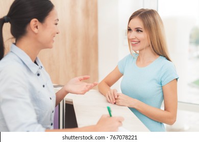 The dark-haired woman works at the reception. She works in a beauty salon. She talks with the client and smiles. - Powered by Shutterstock