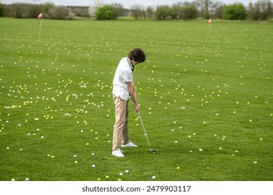 Dark-haired young guy training in a golf club