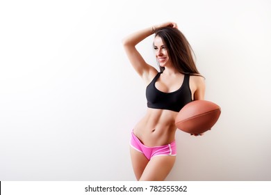 Dark-haired young woman fitness model smile, holds a  rugby ball 
 and seductively posing on white isolated background - Powered by Shutterstock