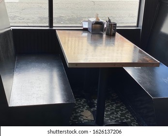 Darkly Lit Empty Restaurant Booth Table Next To Windows Casting Shadows