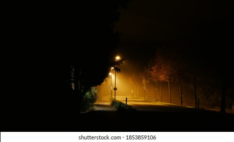 Darkness shapes like a cave revealing the lonely street with fog and glowing street lights in november during the corona pandemic - Powered by Shutterstock