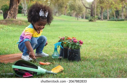 Dark-skinned girl planted flowers in the ground at the park, protect the environment - Powered by Shutterstock