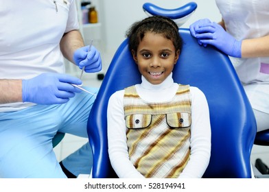 A Dark-skinned Girl Sitting In The Dental Chair At A Reception At The Dentist