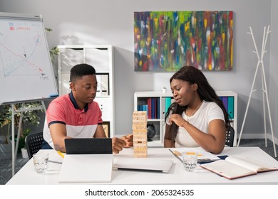 Dark-skinned Man With A Beautiful Woman Relax In The Corporate Office From Work, In Front Of Them Tablet Documents, Friends Play Wood Block Stacking, Have Fun, Stress Reduction