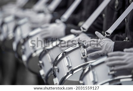 Dark-skinned military drummers play on white drums, in white gloves and with white instrument straps. Close-up, selective focus.