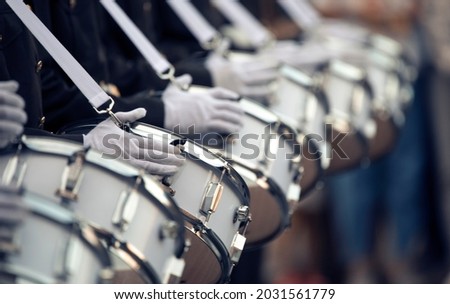Dark-skinned military drummers play on white drums, in white gloves and with white instrument straps. Close-up, selective focus.