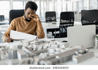 Dark-skinned young architect working in the office and looking tired - Powered by Shutterstock