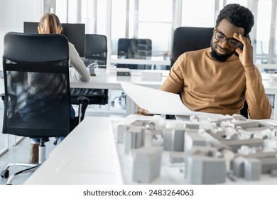 Dark-skinned young architect working in the office and looking tired - Powered by Shutterstock