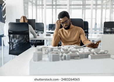 Dark-skinned young architect working in the office and looking tired - Powered by Shutterstock