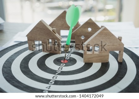 Dart arrow or dartboard hitting on number target center with miniature wooden house models. Success Gold of property mortgage or real estate investment business concept, vintage tone, soft focus