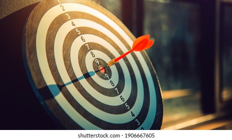 Dart arrow hit on bulleyes of dartboard to represent that the business reached the target  with dark tone picture style. Target and goal as concept.