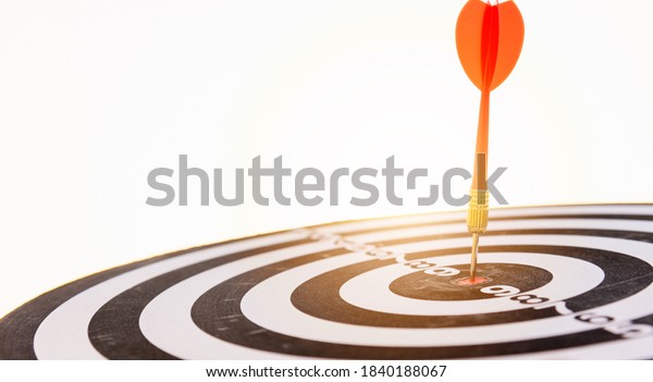 Dart arrow hitting to center on bullseye\
(bull\'s-eye) dartboard is the target of purpose challenge business\
at sunset, expert marketing strategy target, objective financial\
and goal success