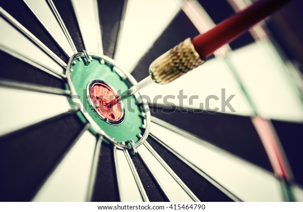 Dart\
arrow hitting in the target center of\
dartboard