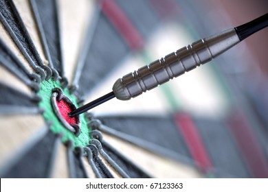 Dart In Bulls Eye Of Dartboard With Shallow Depth Of Field Concept For Hitting Target