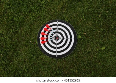 Dartboard, And Five Darts On A Green Lawn