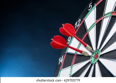 Dartboard on a blue background with arrows hitting the center target - Shutterstock ID 629703779