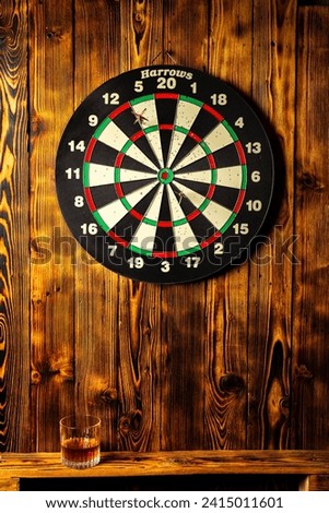 A dartboard with wooden background and a glass of drink
