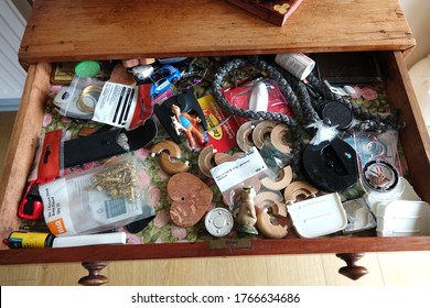 Dartmoor England. Looking inside a domestic drawer with a large jumble of small rarely used articles including, compass, picture hooks, Tin Tin and dog model, decorative rope, knife, film.