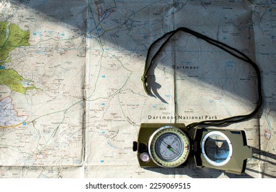 Dartmoor national park map with a compass placed on it. Used for orienteering and navigation. A shadow cuts across the map. Used in the Ten Tors walk and outdoor adventures. Map reading. Copy space.  - Powered by Shutterstock