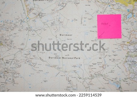Dartmoor national park map with a post it note saying 'Here x' on it. Used for orienteering and navigation. A shadow cuts across the map. Used in the Ten Tors walk and outdoor adventures. Copy space.  Stock fotó © 