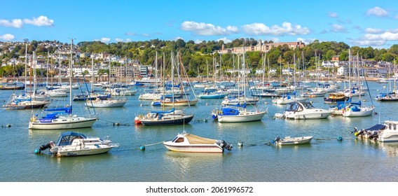 Dartmouth, England - September 2021: Ships moored in Dartmouth harbour with Britannia Royal Naval College in the background, Devon, England, United Kingdom