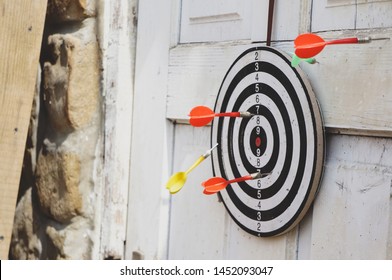 Darts Are Hanging On A White Wooden Door, Three Darts Hit The Target And Two Did Not Hit.                               