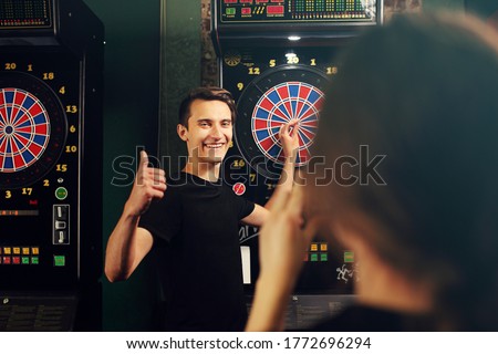 Darts. Young people throw darts at the target. Friendly game in a pub.