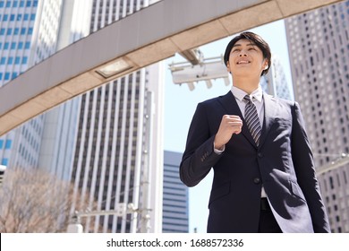 A dashing Japanese businessman walks in the office district. - Shutterstock ID 1688572336