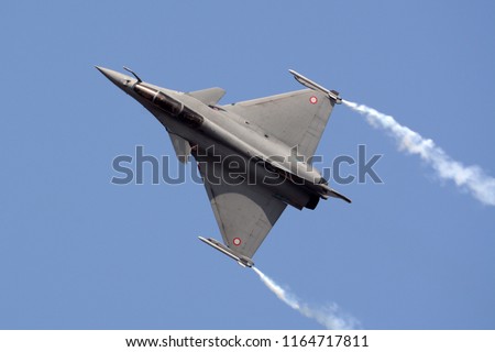 Dassault Rafale fighter jet flying with smoke trails.
