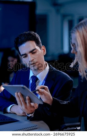 A data analyst scrolls through complex visualizations on a tablet comparing results against code displayed onscreen working late to finalize a critical business intelligence report.