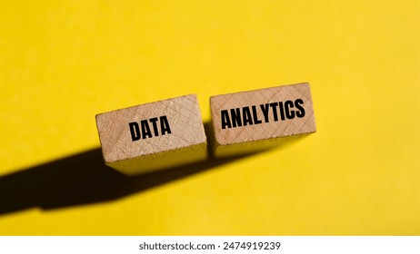 Data analytics message written on wooden blocks with yellow background. Conceptual data analytics symbol. Copy space.