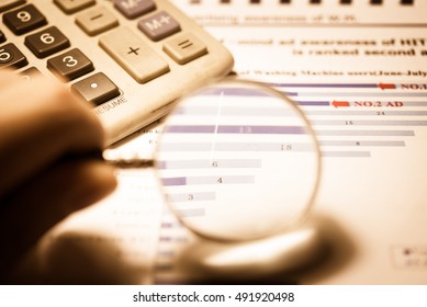 Data analyzing in Forex market with magnifying glass, pen and calculator : the charts and summary info on paper. Charts of financial instruments for technical analysis. - Shutterstock ID 491920498