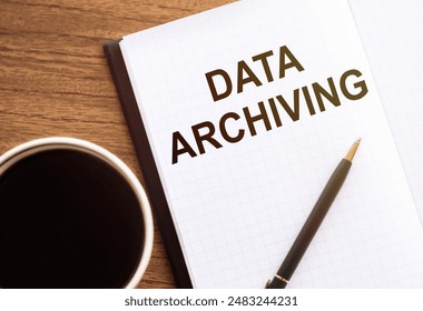DATA ARCHIVING text written on a wooden background with paper sheet and pen