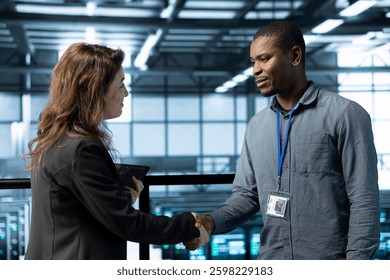Data center admin meeting with supervisor verifying workspace security. Server room IT employee doing welcoming handshake with inspector arriving in facility to scan infrastructure