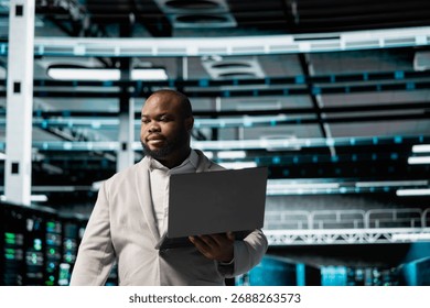 Data center admin using laptop to automate errors detection, troubleshooting backend operations. Server hub IT expert monitoring components for potential failures, conducting regular security audits