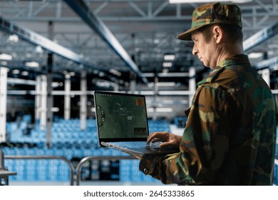 Data center army officer in uniform checking missile targeting software on laptop. Military professional analyzing digital crosshair display in secure server farm facility