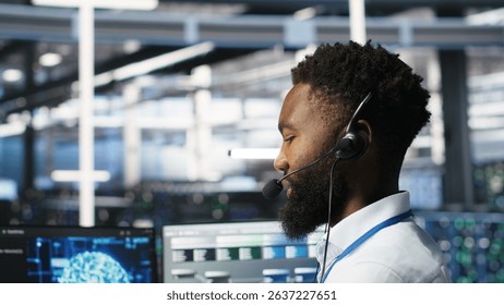 Data center employee talking in headset mic, coordinating technicians setting up hardware for artificial intelligence deployment. Server room worker engages in remote call with engineers, camera B