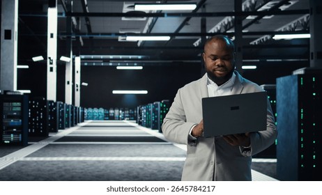 Data center engineer coding on laptop, doing software updates for mainframes. Server farm IT professional typing on notebook keyboard, optimizing infrastructure, camera A