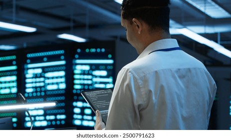Data center engineer responsible for installation and repair of networking equipment solving tasks on device. IT professional doing maintenance on server room infrastructure using tablet, camera A